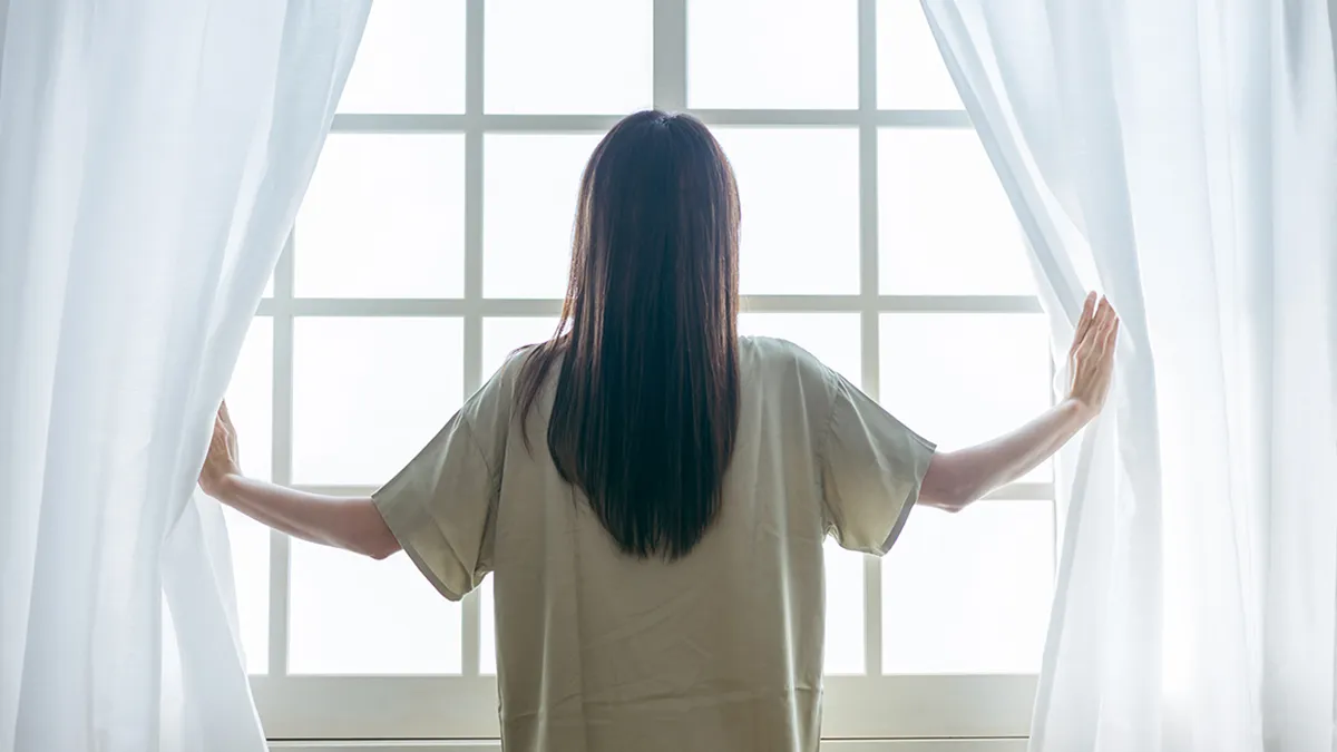 朝、窓を開ける女性